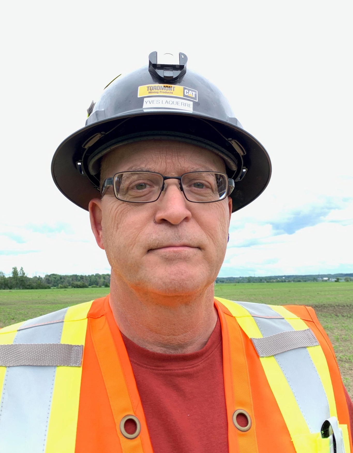 headshot of man in a hardhat outside on a field