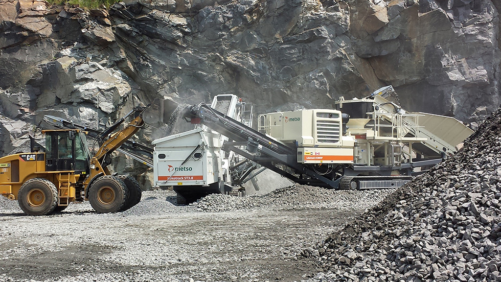 construction vehicles on site, large dirt and rock piles in the background