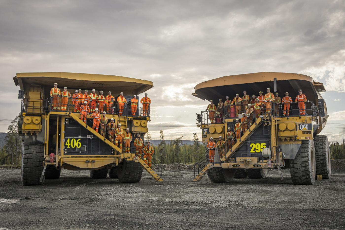 group of construction workers standing on two construction vehicles, cloudy sky