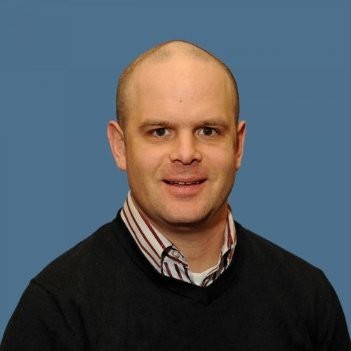 Headshot of man, blue background