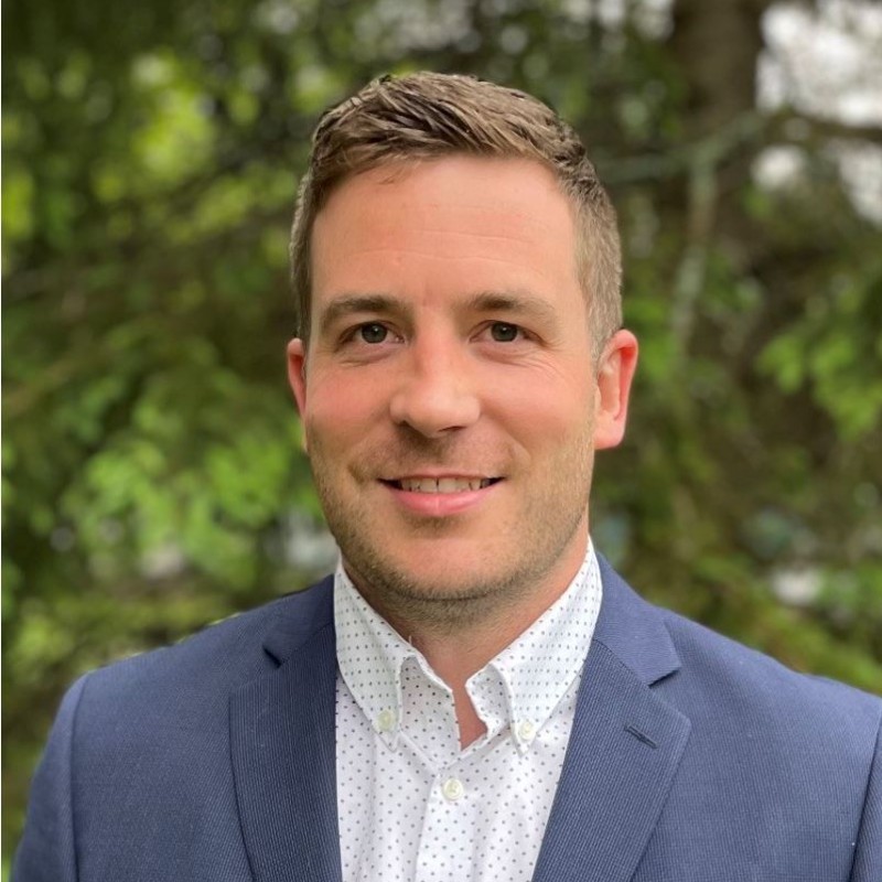 headshot of man in front of greenery