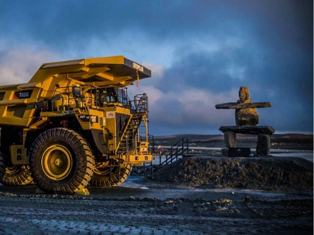 A mining truck drives by an Inukshuk